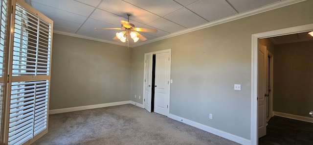 carpeted spare room featuring baseboards, a paneled ceiling, ceiling fan, and ornamental molding