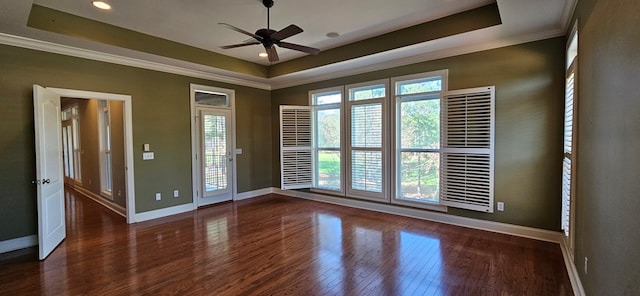 spare room with crown molding, ceiling fan, baseboards, a tray ceiling, and wood finished floors