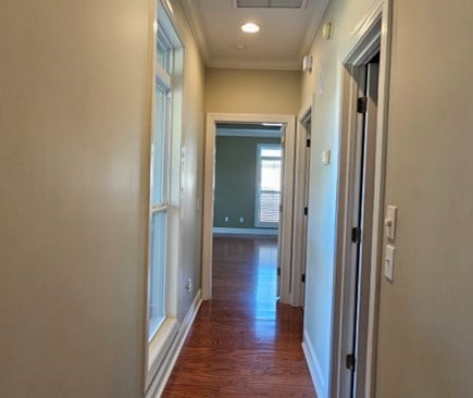 hall featuring visible vents, ornamental molding, dark wood finished floors, recessed lighting, and baseboards