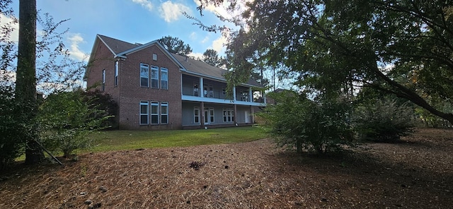 rear view of house featuring a balcony, a lawn, and brick siding