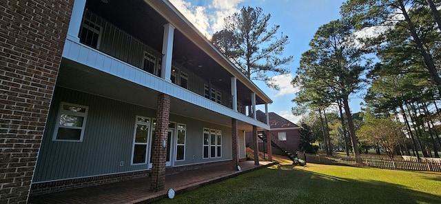 view of side of property with brick siding, stairway, a lawn, and fence