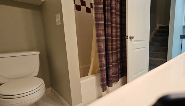 full bathroom featuring toilet, baseboards, and shower / tub combo with curtain