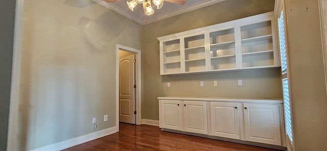 interior space with dark wood-style floors, a ceiling fan, baseboards, and ornamental molding