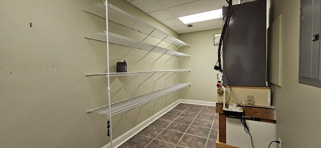 spacious closet with electric panel, a drop ceiling, and tile patterned flooring