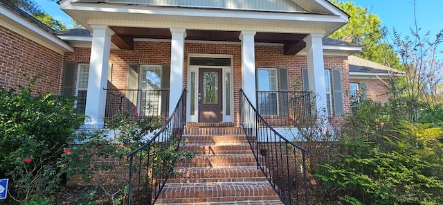 doorway to property with brick siding and a porch