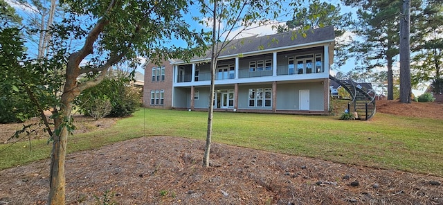 rear view of property with stairs and a yard