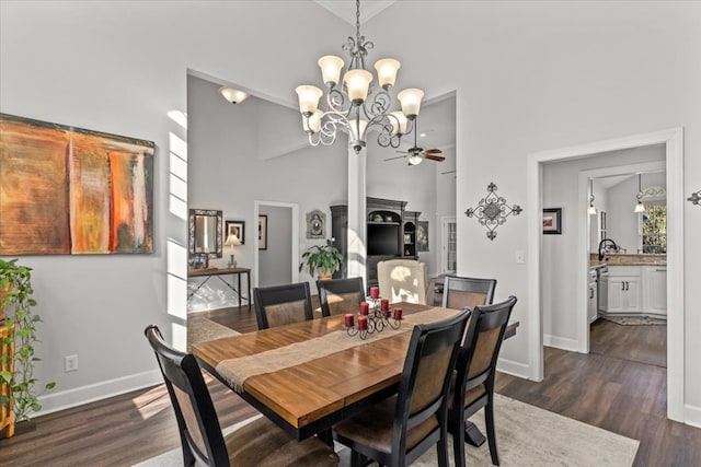 dining room with ceiling fan with notable chandelier, dark wood finished floors, a towering ceiling, and baseboards