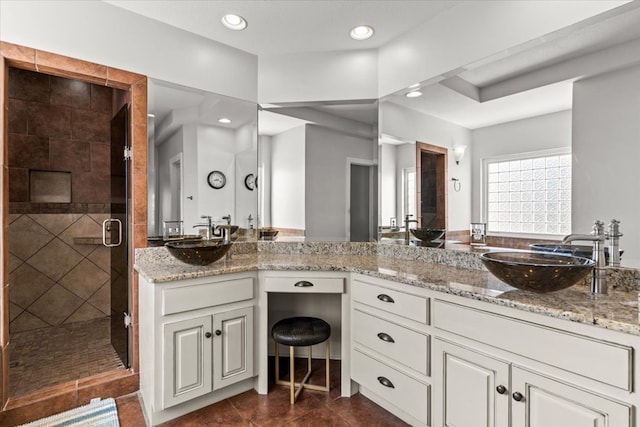 bathroom with tile patterned flooring, a sink, a shower stall, and double vanity