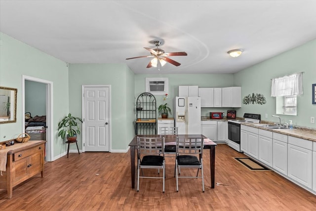 kitchen with light wood-style floors, white cabinetry, a sink, white appliances, and baseboards