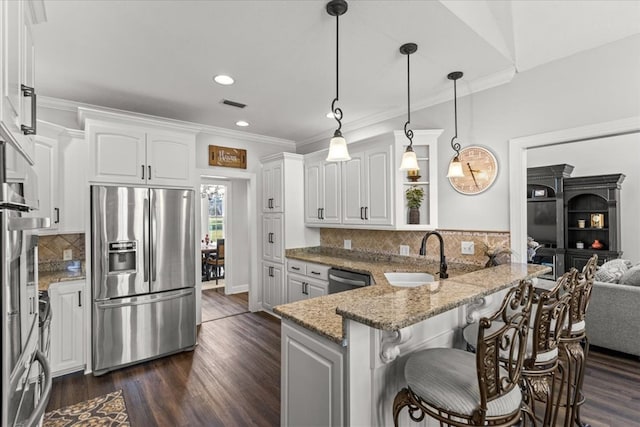 kitchen with a peninsula, appliances with stainless steel finishes, a sink, and white cabinetry