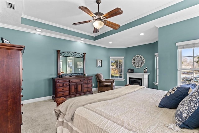 bedroom featuring a fireplace, a raised ceiling, ornamental molding, light carpet, and baseboards