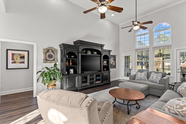 living room featuring ceiling fan, a high ceiling, baseboards, dark wood-style floors, and crown molding