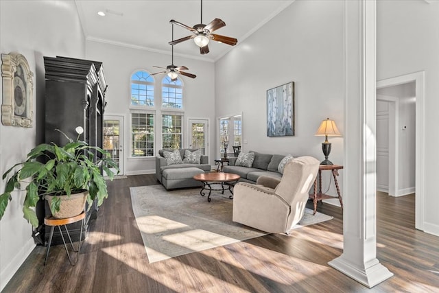 living room featuring ornamental molding, dark wood-type flooring, a towering ceiling, and baseboards