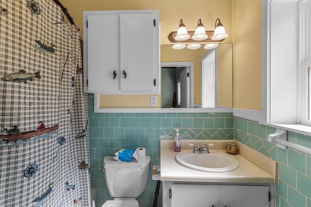 bathroom with vanity, toilet, and tile walls