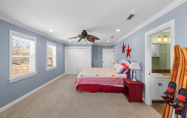 carpeted bedroom with sink, ensuite bath, ceiling fan, ornamental molding, and a closet