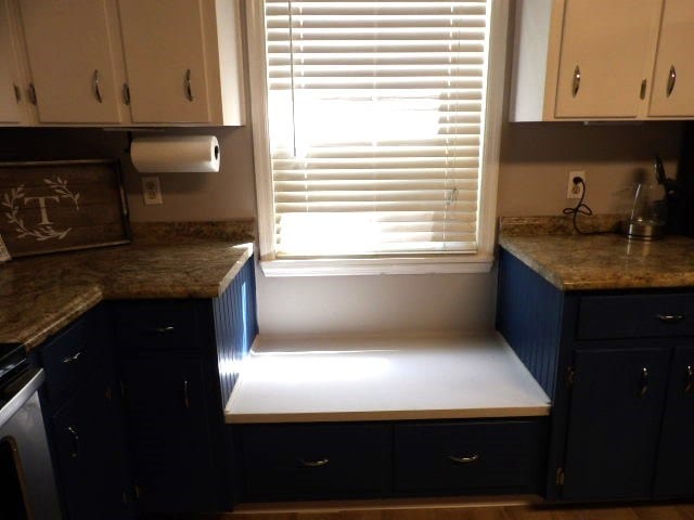 kitchen featuring white cabinetry, range, and light stone countertops