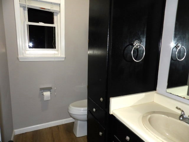 bathroom featuring toilet, wood-type flooring, and vanity