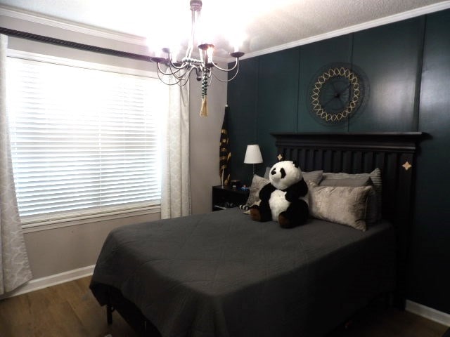 bedroom featuring ornamental molding, a notable chandelier, and wood-type flooring