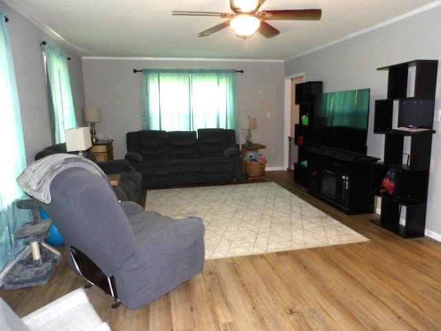 living room with light wood-type flooring, ceiling fan, and crown molding