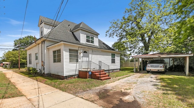 view of front of home with fence, dirt driveway, a front yard, roof with shingles, and a carport