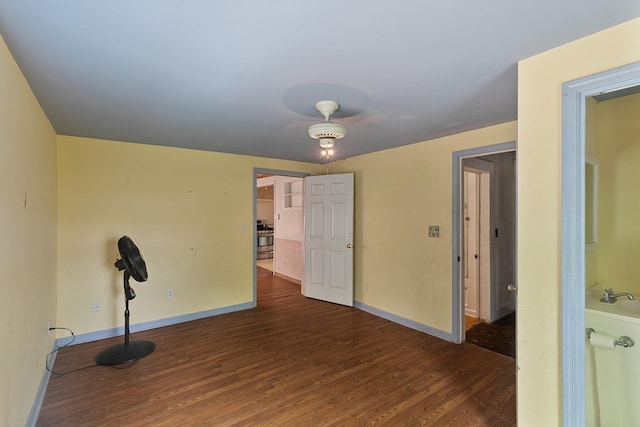 spare room with baseboards and wood finished floors