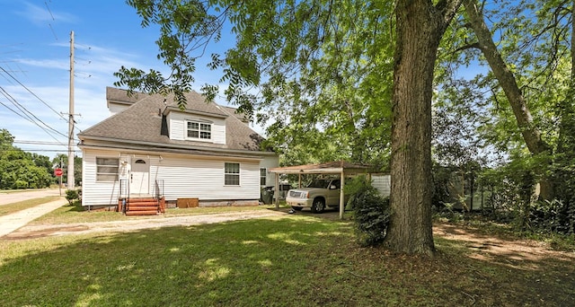 rear view of house with a shingled roof, a carport, and a lawn