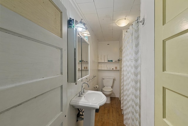 bathroom with toilet, a shower with curtain, a sink, and wood finished floors