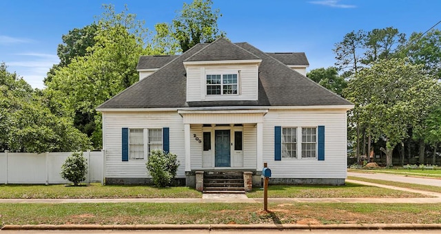view of front of home featuring roof with shingles, a front lawn, and fence