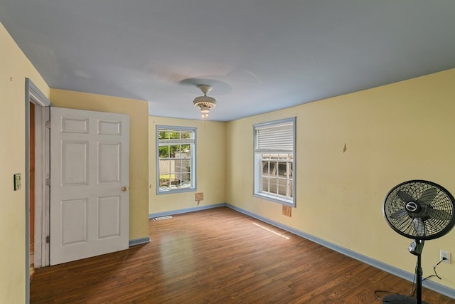 spare room with baseboards, visible vents, and wood finished floors
