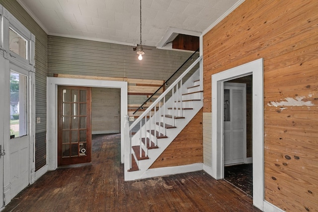 entryway featuring crown molding, wooden walls, hardwood / wood-style floors, and stairway