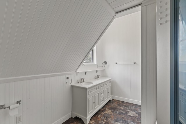 bathroom featuring double vanity, baseboards, stone finish floor, and a sink