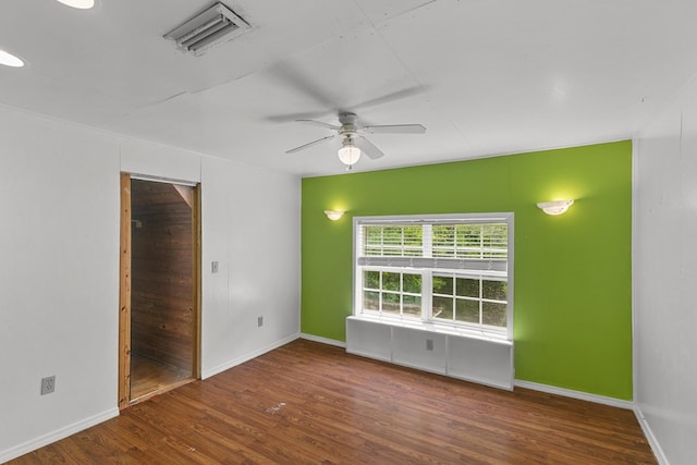 spare room with a ceiling fan, baseboards, visible vents, and wood finished floors