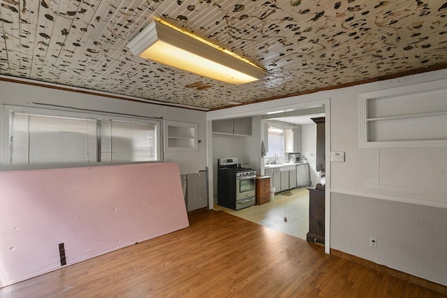 kitchen featuring light countertops, light wood-style floors, gas range, and a sink