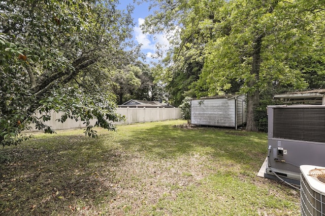 view of yard featuring central air condition unit, a storage shed, an outbuilding, and fence