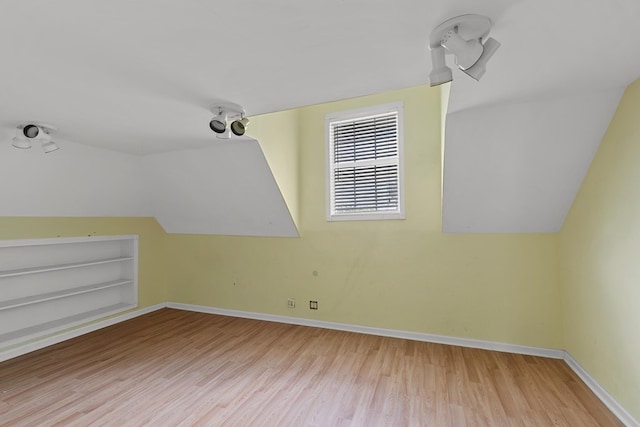 additional living space with built in features, lofted ceiling, baseboards, and wood finished floors