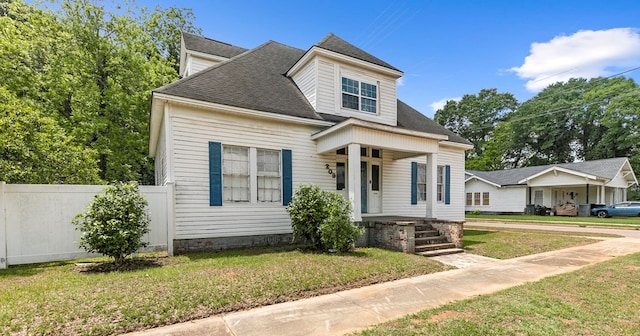 view of front of house with a porch, fence, a shingled roof, and a front yard