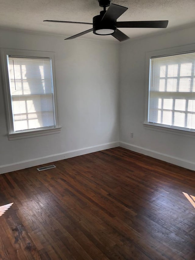 empty room with a textured ceiling, ceiling fan, and dark hardwood / wood-style floors