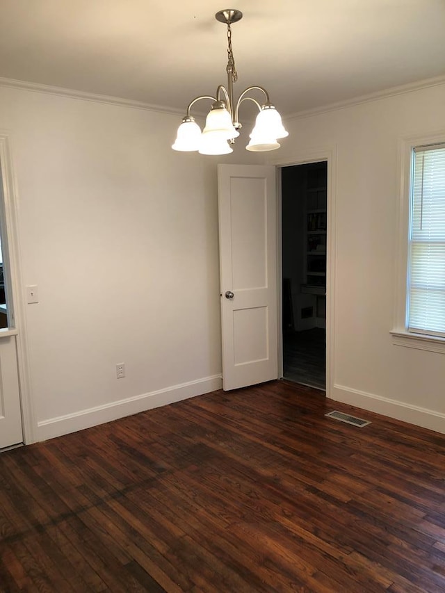 empty room featuring a notable chandelier, dark hardwood / wood-style flooring, and crown molding