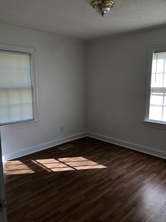 spare room featuring a textured ceiling, crown molding, and dark hardwood / wood-style floors