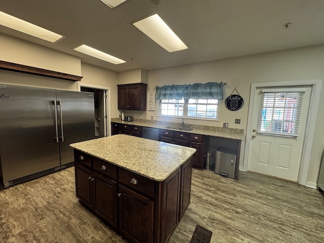 kitchen featuring dark brown cabinetry, visible vents, wood finished floors, stainless steel appliances, and a sink