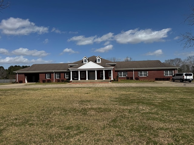 view of front facade featuring covered porch, brick siding, and a front lawn