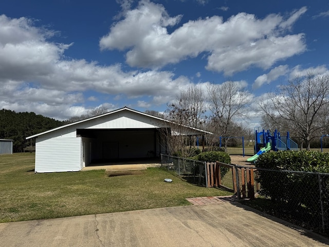 view of front of home featuring a garage, fence, playground community, an outdoor structure, and a front yard