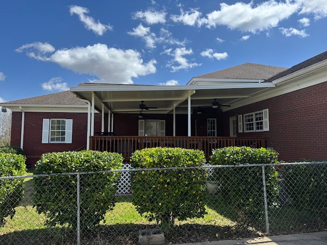 exterior space with fence private yard, a ceiling fan, and brick siding