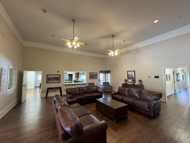 living area with a towering ceiling, dark wood-style floors, and baseboards