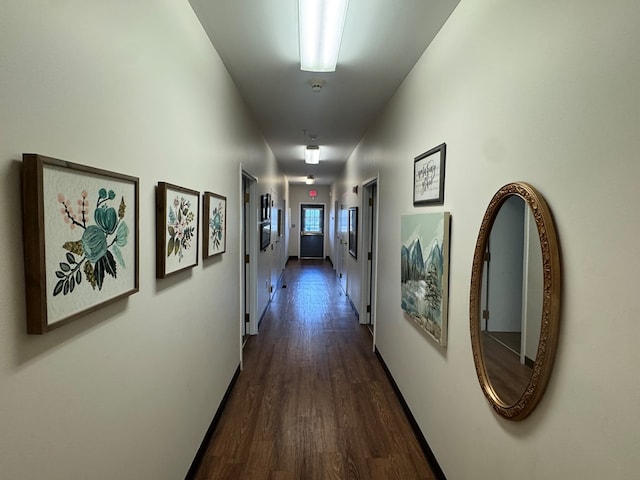 hallway featuring dark wood-style flooring and baseboards