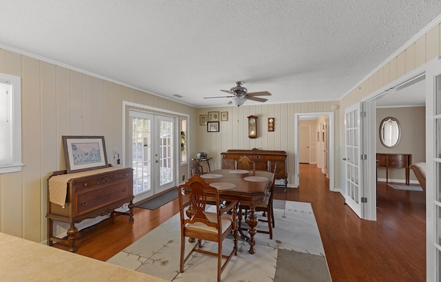 dining space featuring wood-type flooring, crown molding, ceiling fan, french doors, and a textured ceiling