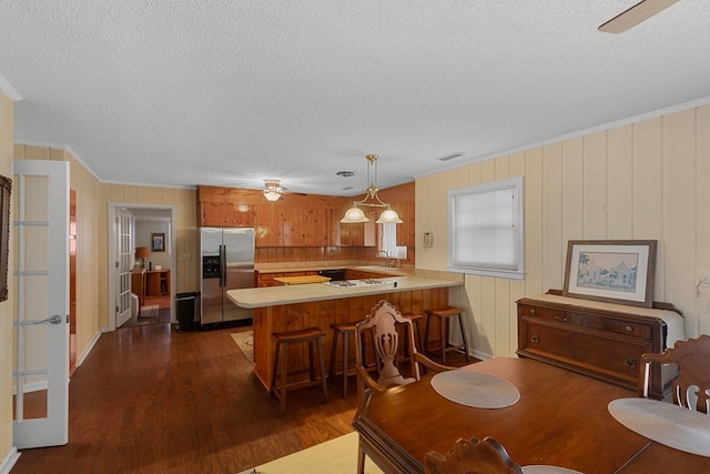 kitchen featuring sink, a kitchen breakfast bar, kitchen peninsula, dark hardwood / wood-style floors, and stainless steel refrigerator with ice dispenser