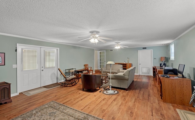 living room with ornamental molding, french doors, light wood-type flooring, and a textured ceiling