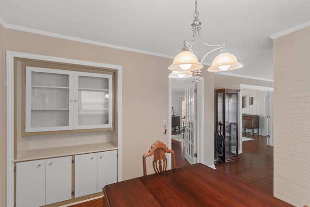 dining space with ornamental molding, dark wood-type flooring, a notable chandelier, and a textured ceiling