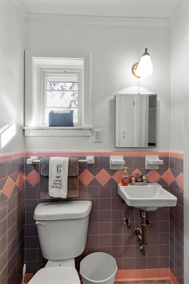 bathroom with tile walls, toilet, crown molding, and sink